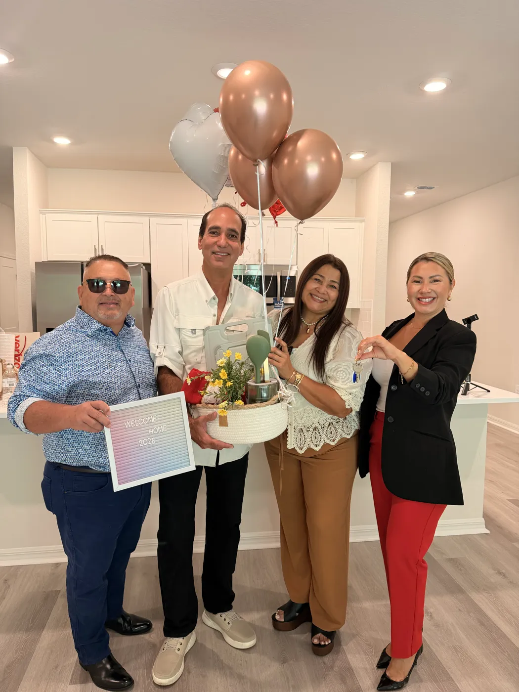 Familia recibiendo su nueva casa con globos y un cartel de Welcome Home