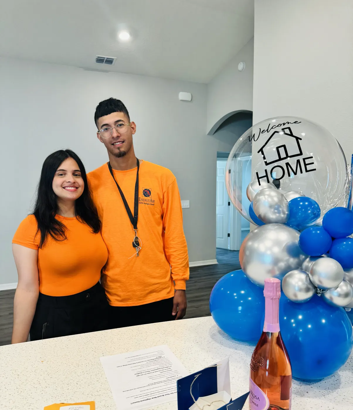 Pareja joven celebrando la compra de su primera casa con globos de Welcome Home
