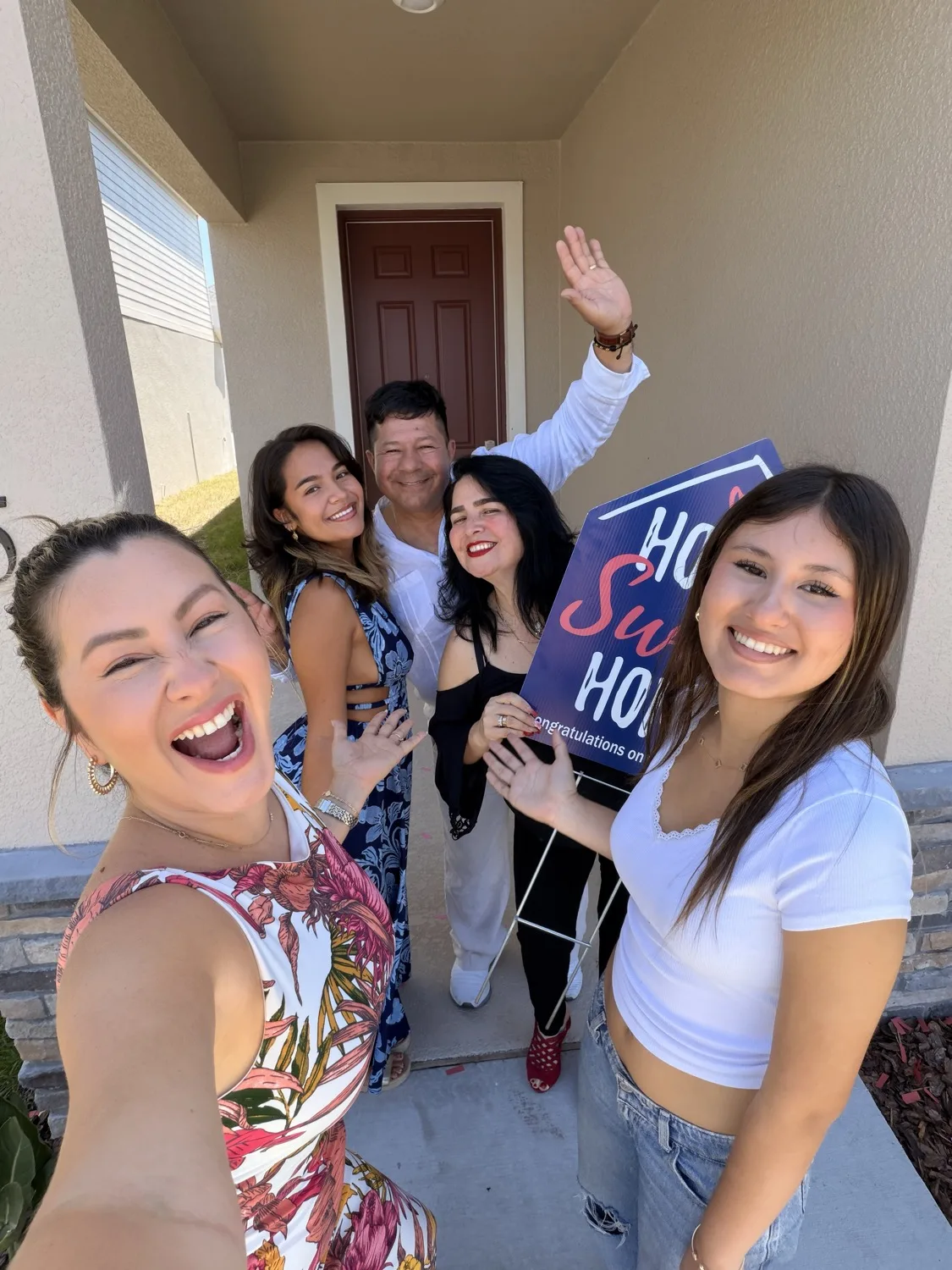 Jenny Caso celebrando con una familia frente a la puerta de su nueva casa